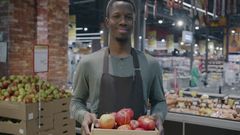 man holding apples in a grocery store