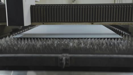 sheet of metal on pointy platform moving under cnc laser cutting machine