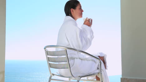 mujer bebiendo un café con vista al mar