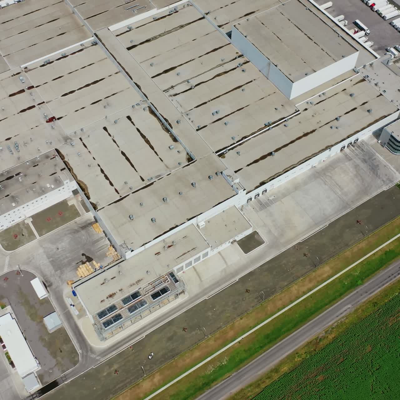Industrial complex. Roofs of manufacture buildings on green field. Car parking for trucks on the territory of factory. Top view.