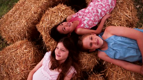 little girls lying on straw in circle with heads together