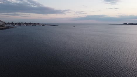 Sobrevuelo-Aéreo-Del-Agua-Del-Océano-Que-Muestra-El-Barco-De-Pesca-Que-Llega-Al-Puerto-De-Punta-Del-Este-En-Uruguay-Por-La-Noche