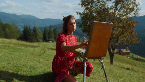 talented woman drawing easel on green meadow. girl artist painting nature.