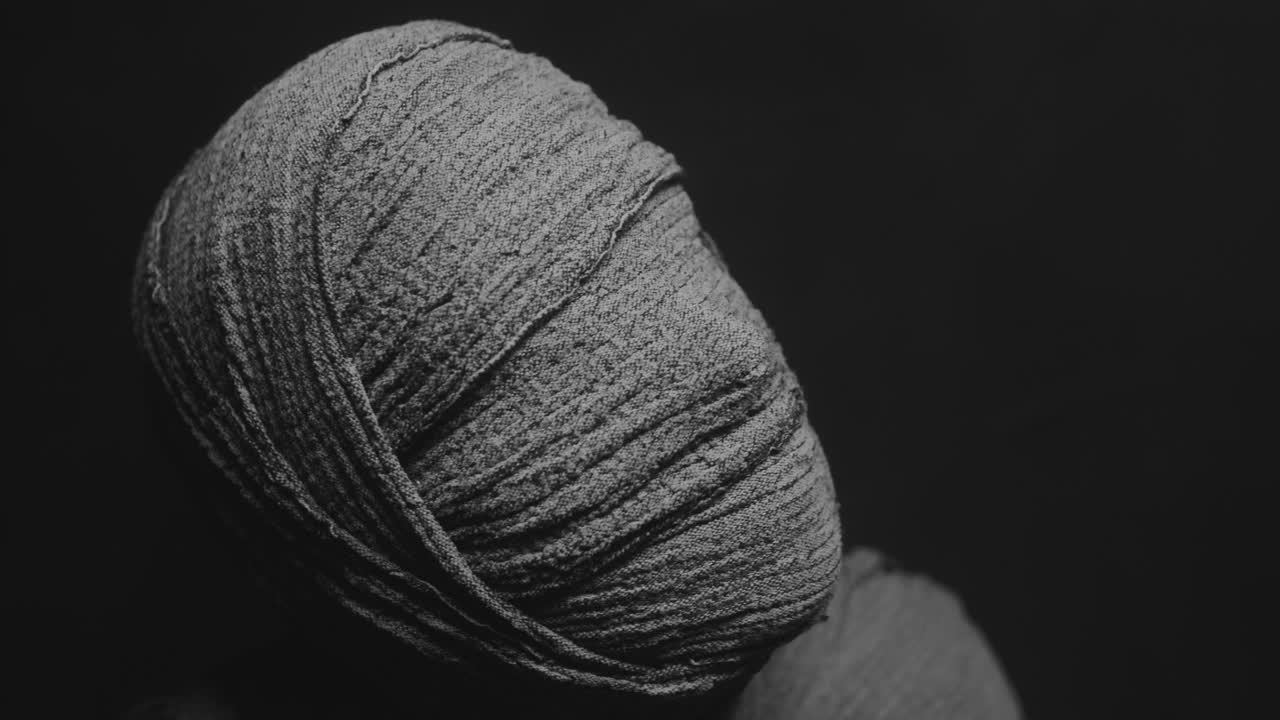 A mummy of a woman on a dark backdrop rises her head