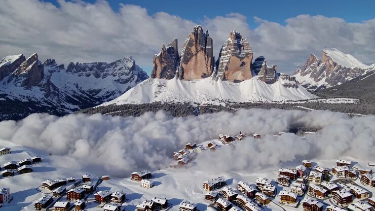 Riprese video aeree di un villaggio alpino innevato con uno spettacolare sfondo montano