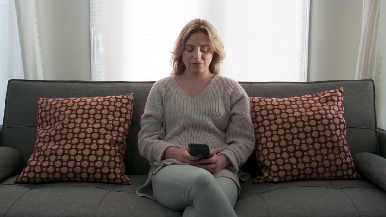 Young blonde Millennial woman looking at her cell phone