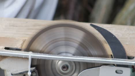 close-up of a man sawing a piece of wood.