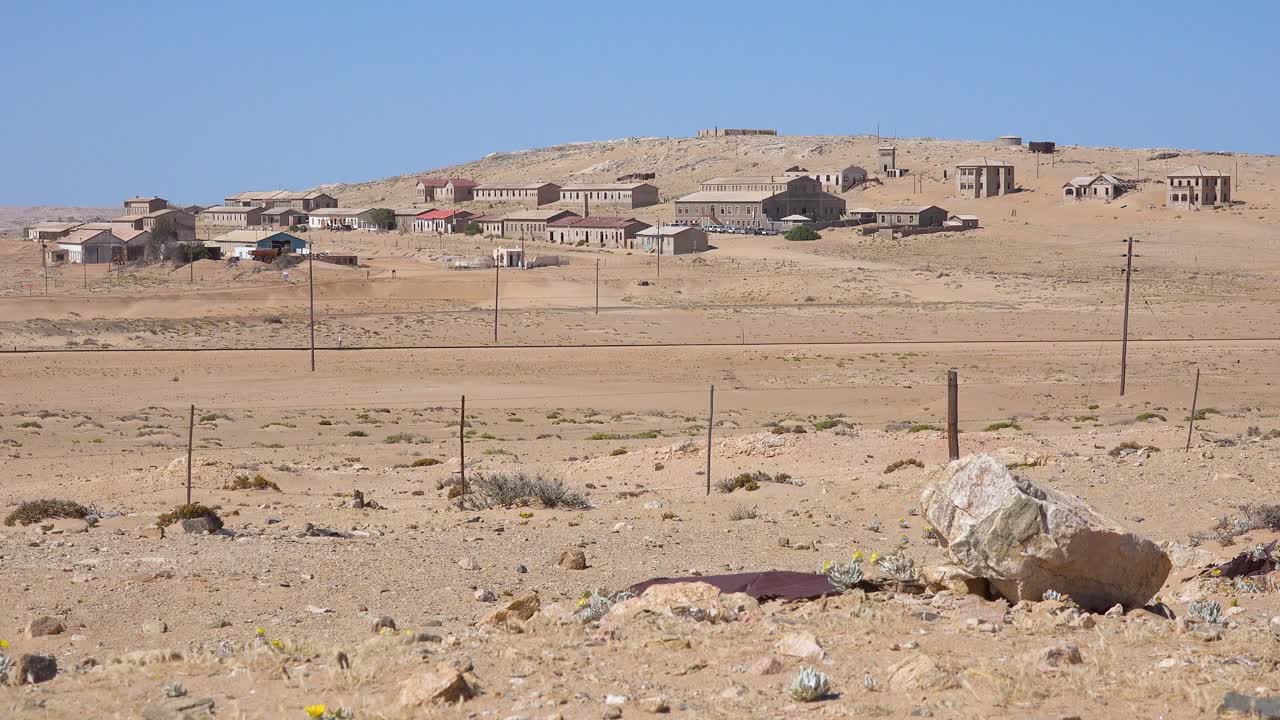 Inquadratura esterna introduttiva di edifici abbandonati nel deserto del Namib nella città fantasma di Kolmanskop, Namibia 1