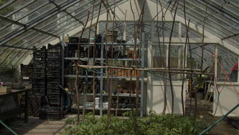 gardening equipment and plants inside glass greenhouse