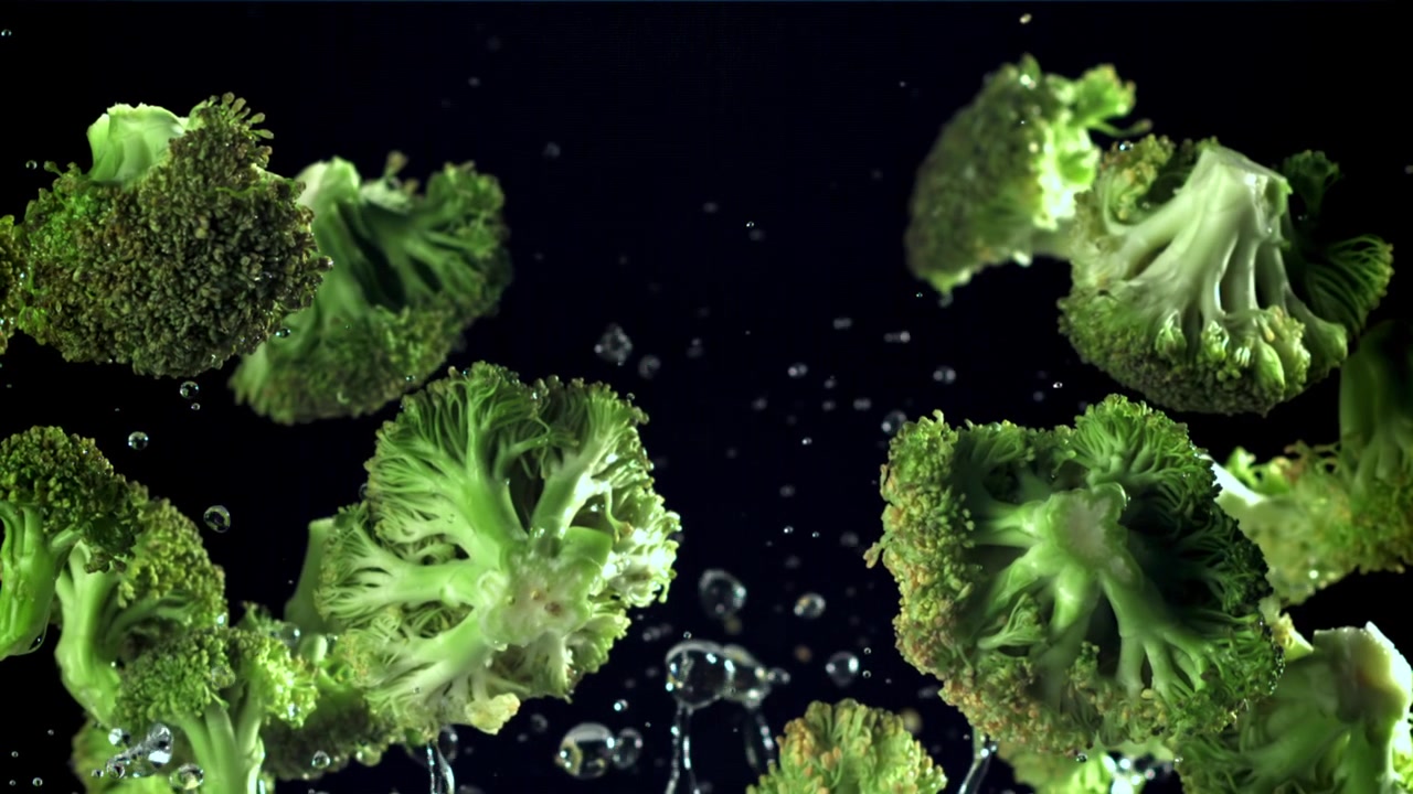 Pezzi di broccoli freschi che cadono e schizzano nell'acqua