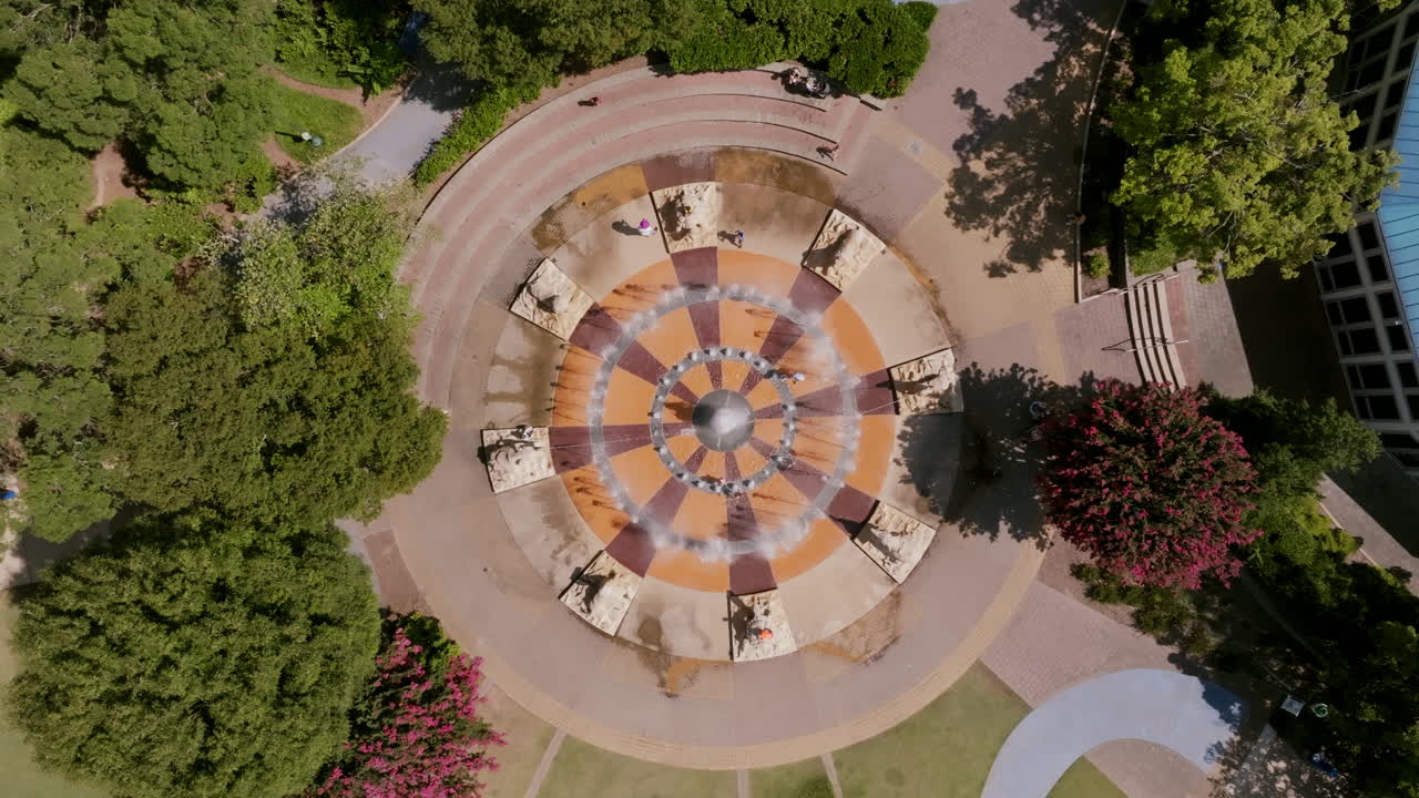 Drone view of Chattanooga’s park fountain plaza with surrounding trees, pathways, and a blue-roofed carousel in Coolidge Park