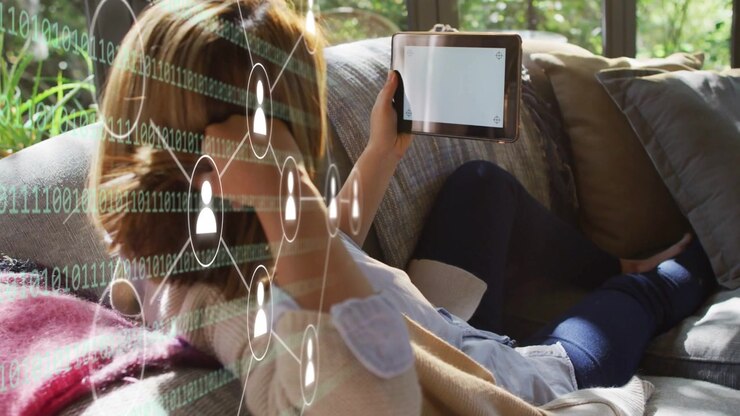 Midadult woman reclining on sofa holding pad, blank-screen starting tech network overlay over torso