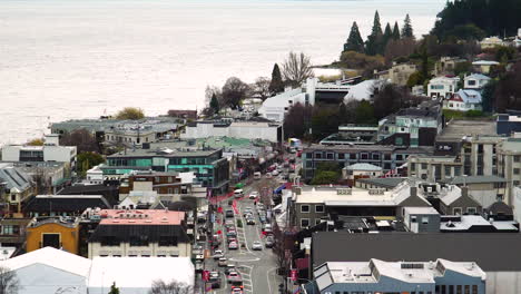 Zooming-out-shot-of-Queenstown-central-view-on-the-shores-of-the-South-Island’s-Lake-Wakatipu,-set-against-the-dramatic-Southern-Alps-at-background