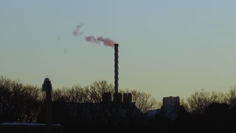 steam billowing from tall exhaust stack after sunset, during mid-winter near saco, maine. wide shot. slow motion.