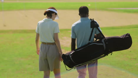 caucasian woman and african american man on the golf course.