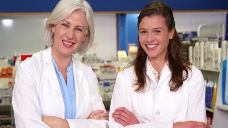 smiling pharmacists standing with arms crossed in pharmacy