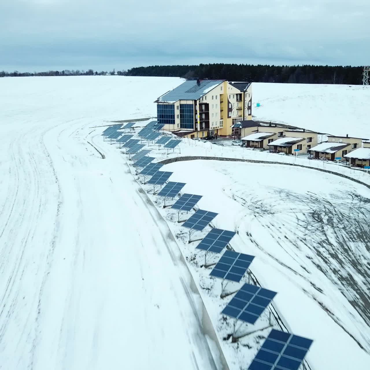 Hotelový komplex v horách se solárními panely na sněhu. Řady sněhem pokrytých solárních panelů v malé solární elektrárně.
