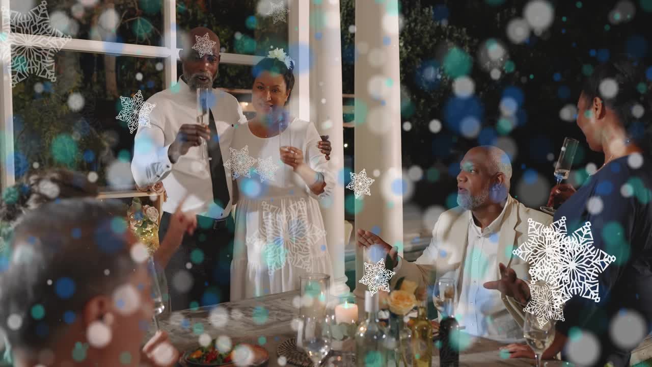 Standing couple celebrating raising glass and toasting, guests clapping, snowflake overlay drifting