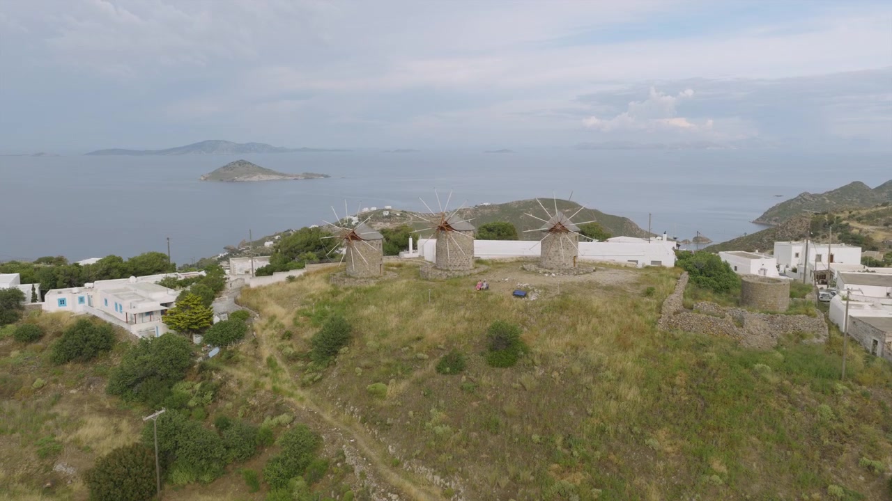 Luftfoto af Patmos' traditionelle stenmøller på toppen af en bakke, med udsigt over Det Ægæiske Hav og fjerne øer