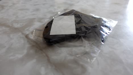 black mask in its packaging on a marble counter, no persons