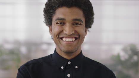 portrait-of-young-mixed-race-man-smiling-cheerful-looking-at-camera-enjoying-successful-job-opportunity-ambitious-male-in-office-workspace-background