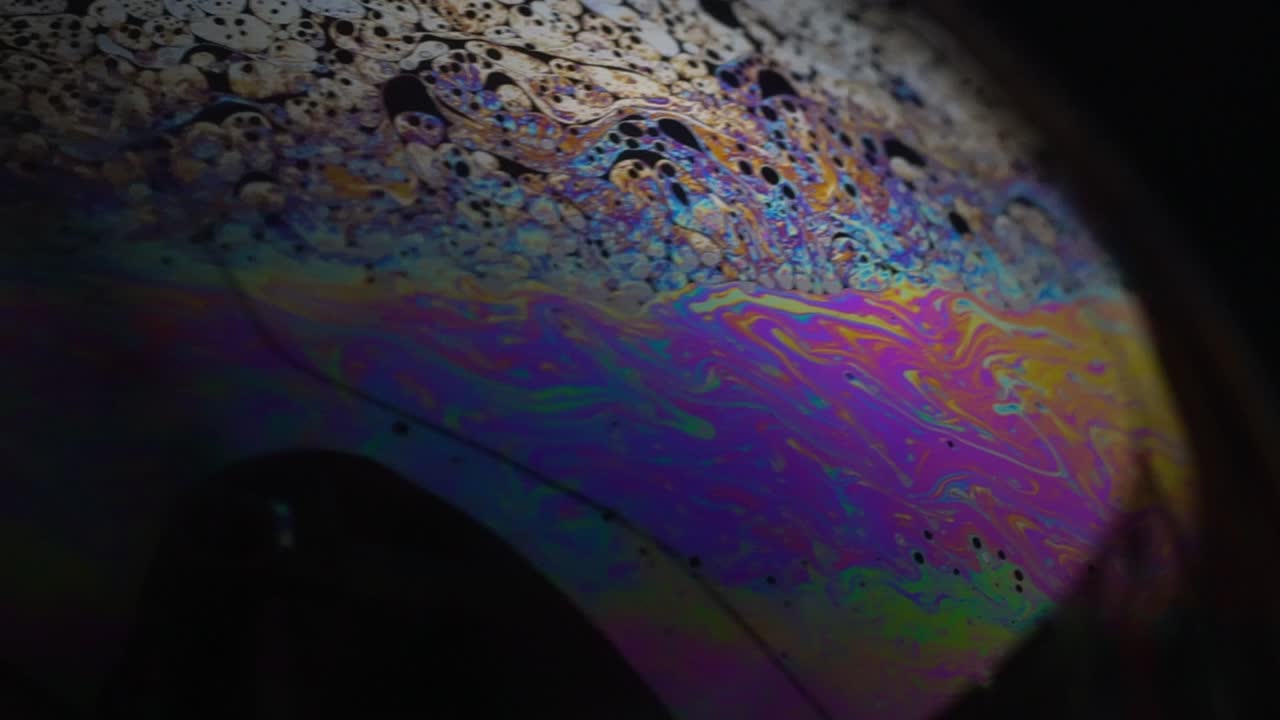 Abstract pattern, chaotic rainbow texture inside soap bubble, Macro. Slow motion.