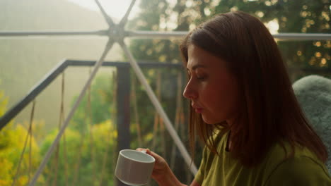 worried woman distracts from work for break to take sip of fresh tasty coffee. woman continues to hold cup in right hand gazing thoughtfully into middle