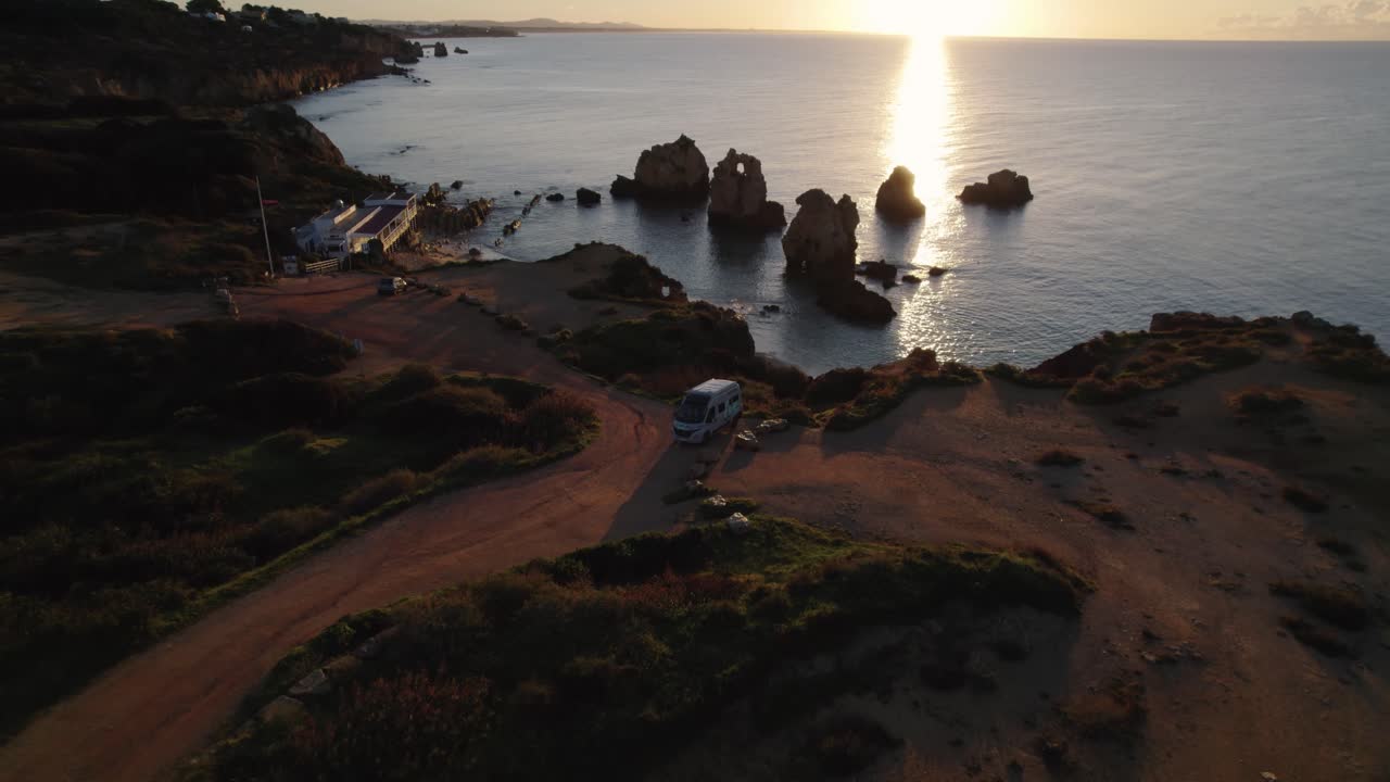 Luftaufnahme eines geparkten Wohnmobils an Praia dos Arrifes, im glühenden Sonnenaufgang an der portugiesischen Küste