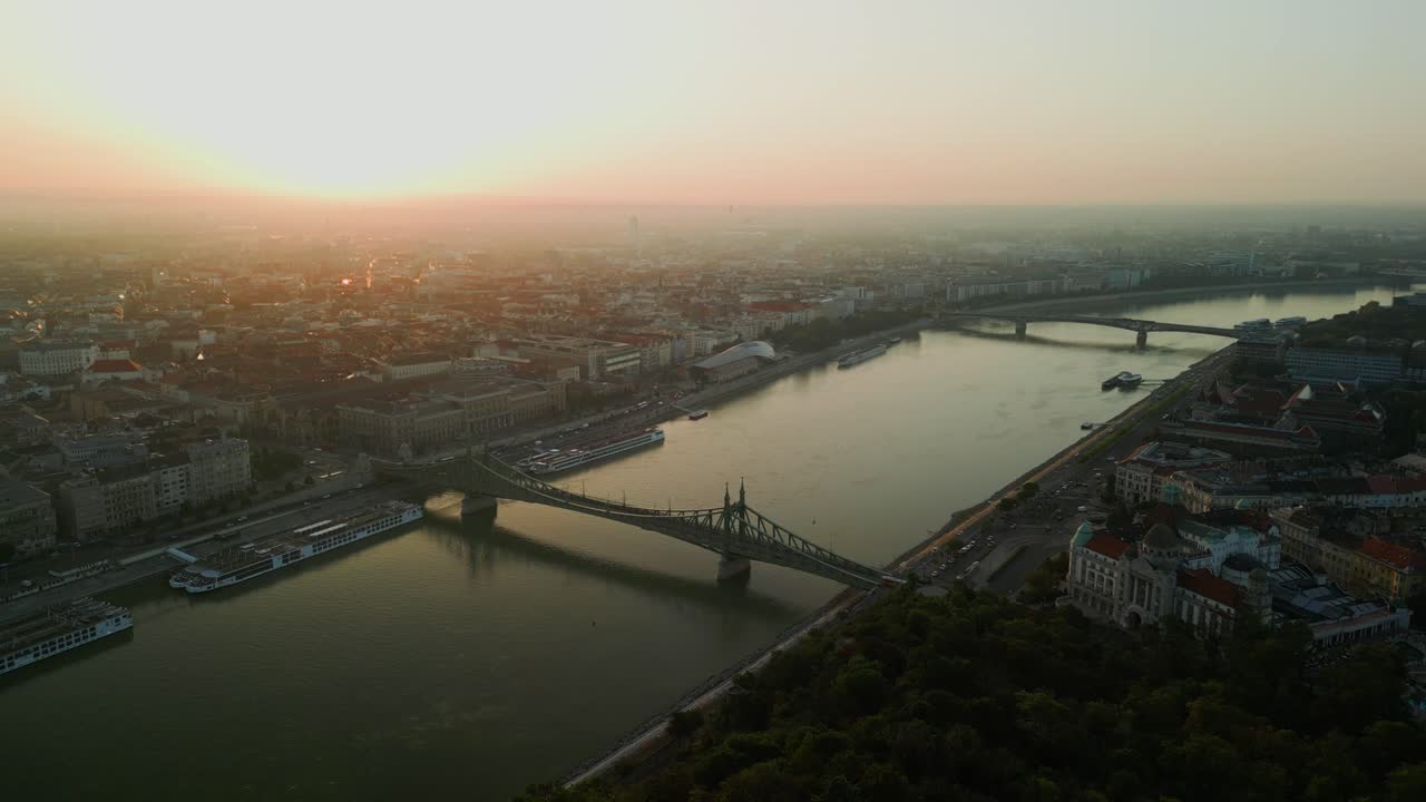 Aerial dolly from Liberty Statue Gellert Hill to Budapest bridge over Danube during golden hour with long shadows and light