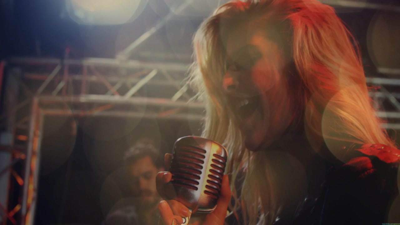 Vertical video: Female singer singing opening note, gripping mic, performing music with guitarist