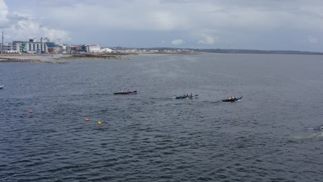 Die-Drohne-Dreht-Sich-Und-Zeigt-Currach-Bootsrennfahrer,-Die-Schnell-Mit-Holzrudern-In-Die-Bucht-Von-Galway-Rudern