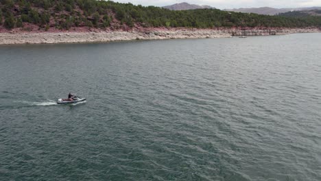 Girl-riding-jet-ski-in-Flaming-Gorge-Reservoir-in-Utah,-aerial-view