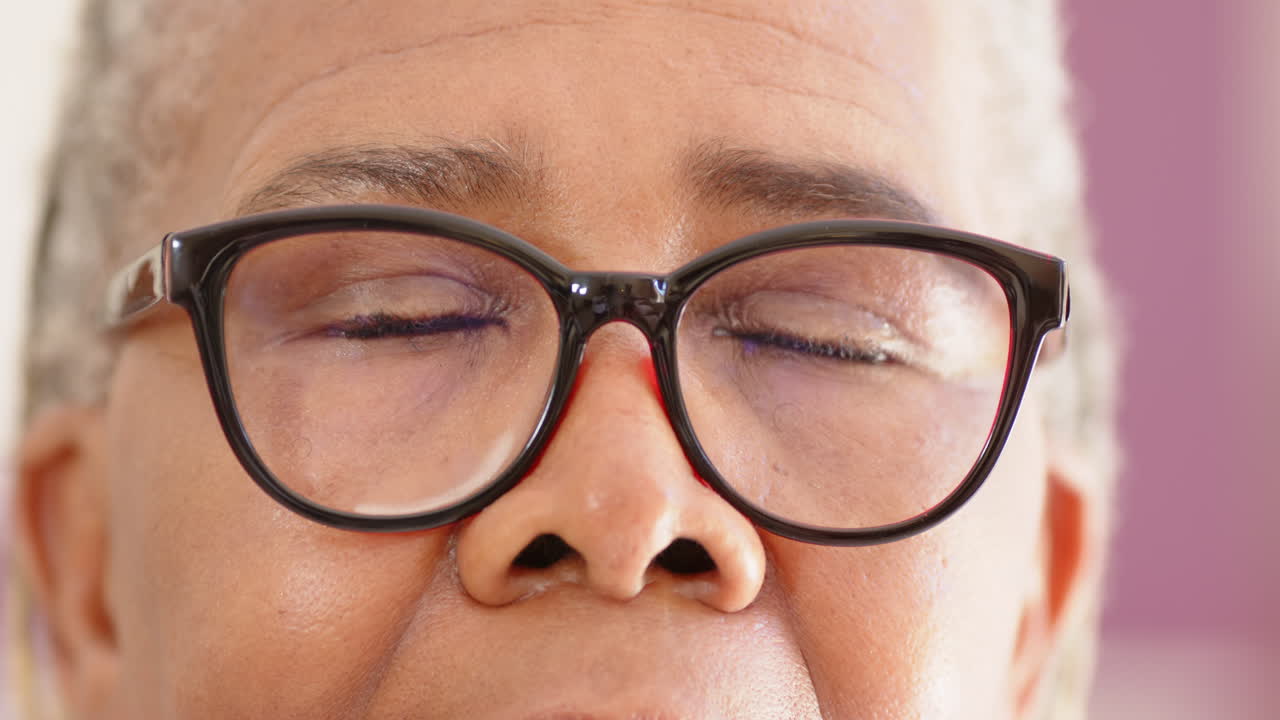 Elderly woman wearing glasses looking thoughtfully, showing wisdom and experience, at home