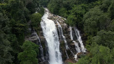 slow aerial forward flight over beautiful hidden waterfall in lush jungle