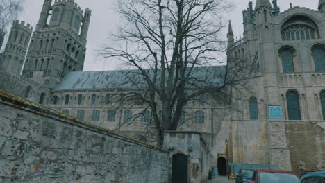 Low-angle-shot-of-towers-of-Ely-cathedral-in-front-of-a-car-parking-lot-in-Cambridgeshire,-England-on-a-cloudy-day