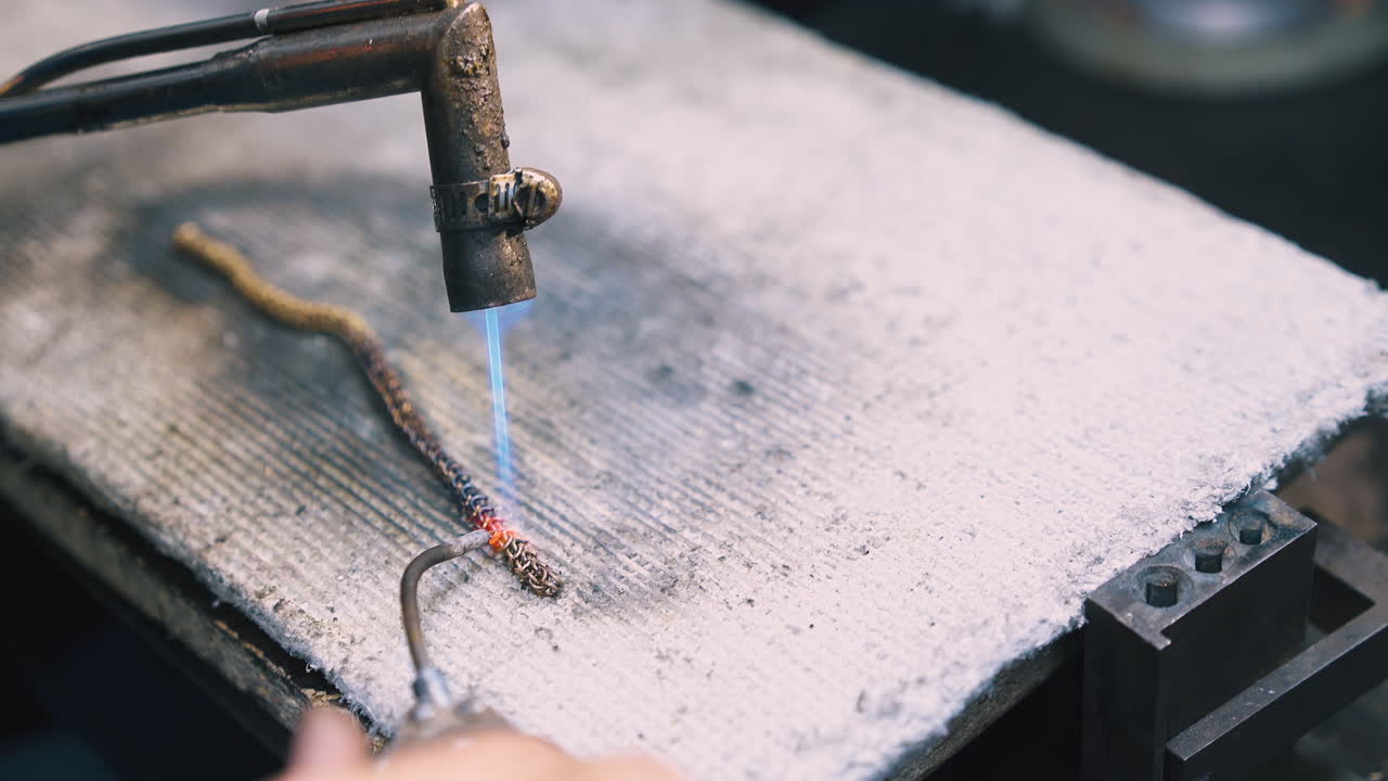 보석공은 특별한 용접 클로즈업으로 체인 링크를 연결합니다.