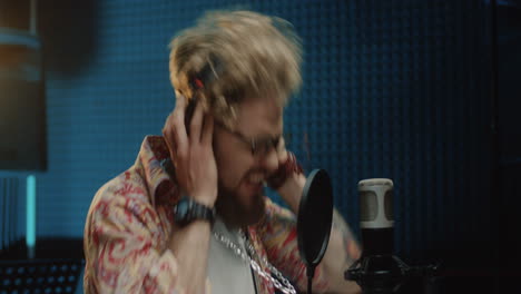 close up of the young handsome and stylish hipster male singer recording a song in the studio while singing in the mic