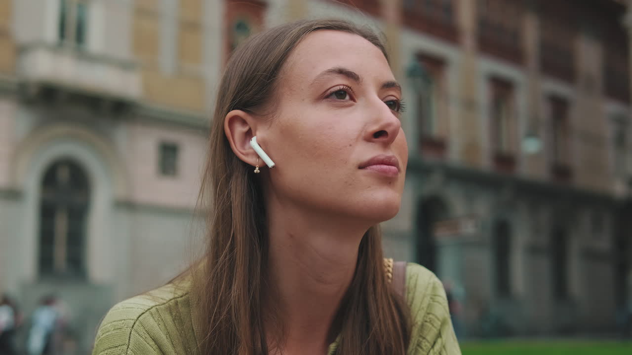 Young Woman Listening to Music with Wireless Earbuds Outdoors