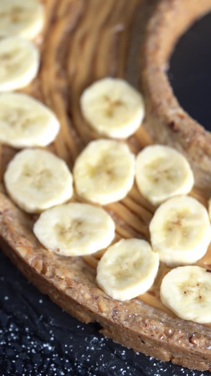 A chief adds banana slices to a cake, close up shot, insert shot