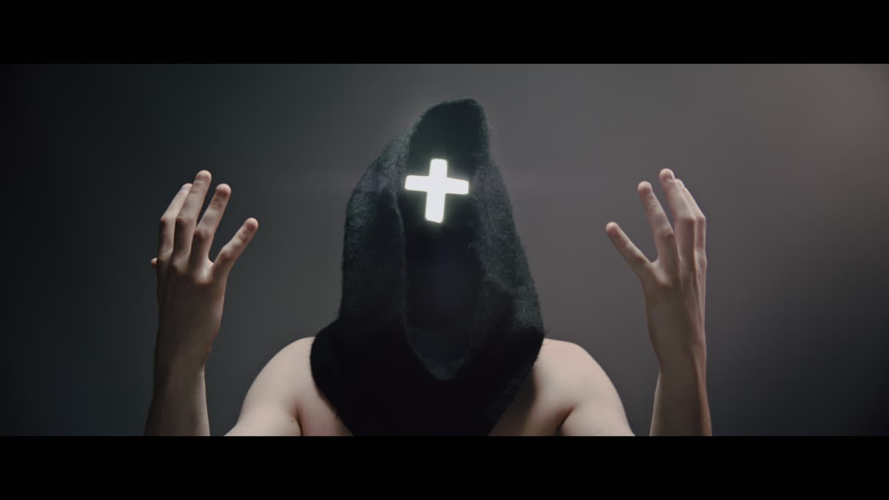 Masked man with cross of light glowing on his face prays