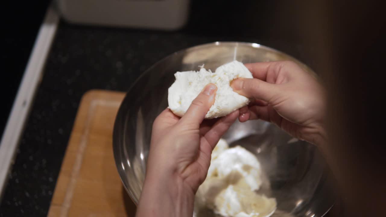 A woman chef tearing mozzarella ball to smaller pieces