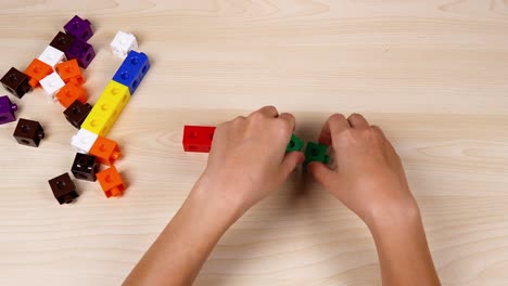 hands assembling colorful linking cubes on table