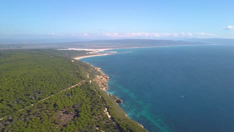 vista aérea de un gran acantilado en la costa mediterránea de españa con una ciudad al fondo