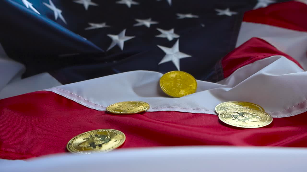 Close up or closeup view of golden shiny and reflective metallic Bitcoinc cryptocurrency money coins scattered on top of an American United States flag. Flag is wrinkled and starts and stripes visible