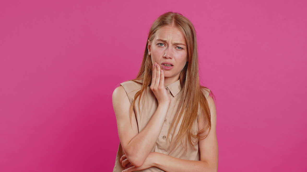 Young woman touching cheek, closing eyes with expression of terrible suffer from painful toothache