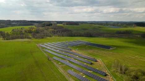 solar farm with many panels surrounded by agricultural fields in sunlight and clouds