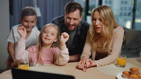 familia agitando las manos cámara portátil en casa. padres hijos haciendo videollamada.