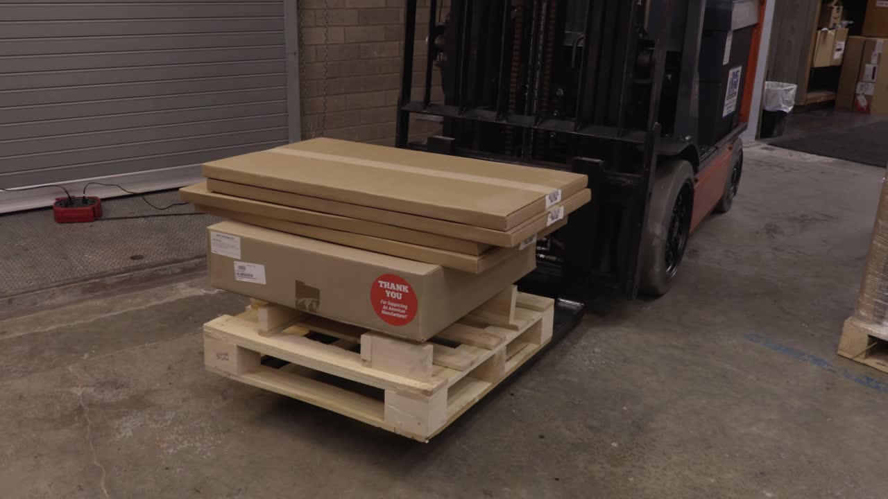 전동 지게차는 팔레트와 상자를 앞으로 이동시킨 후 프레임 밖으로 들어올립니다.