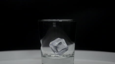 ice cubes slowly falling into scotch glass