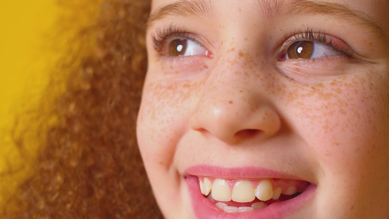 retrato de estudio de una chica sonriente con cabello rojo contra un fondo amarillo